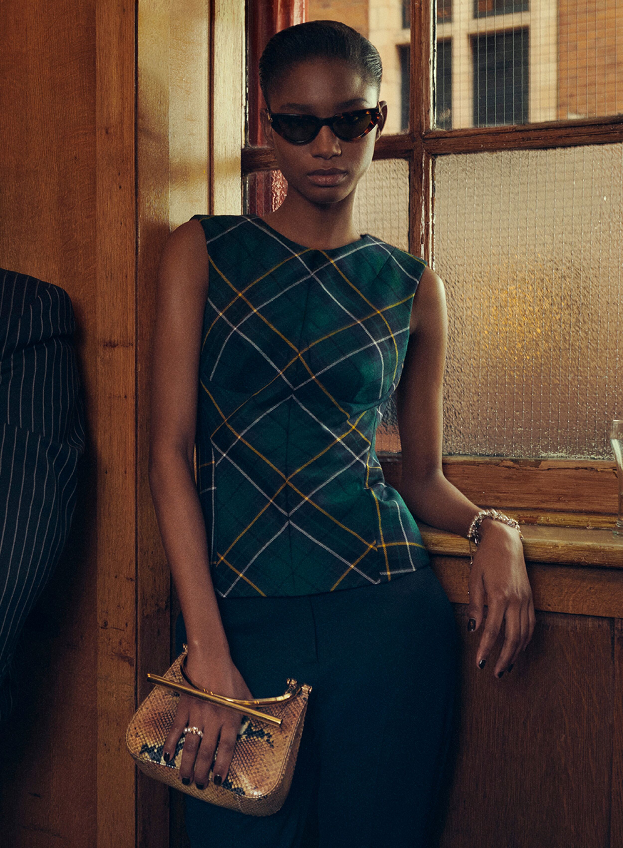 Women in a tartan top and T-Bar mini bag