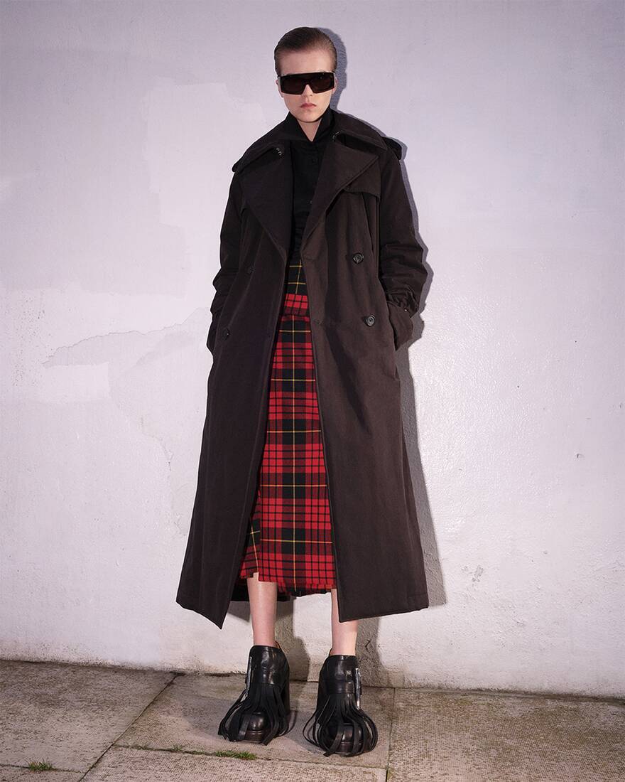 Women in a tartan kilt with a overcoat and boots