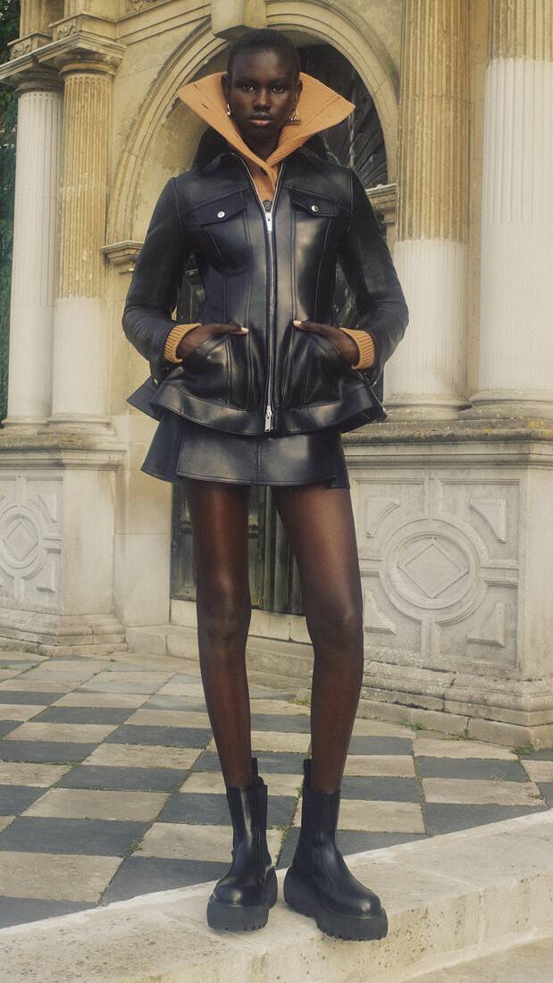 Model wearing McQueen leather peplum jacket and mini skirt
