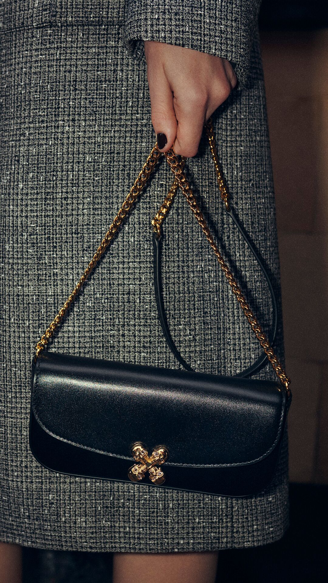 Women holding a black McQueen skull flower bag