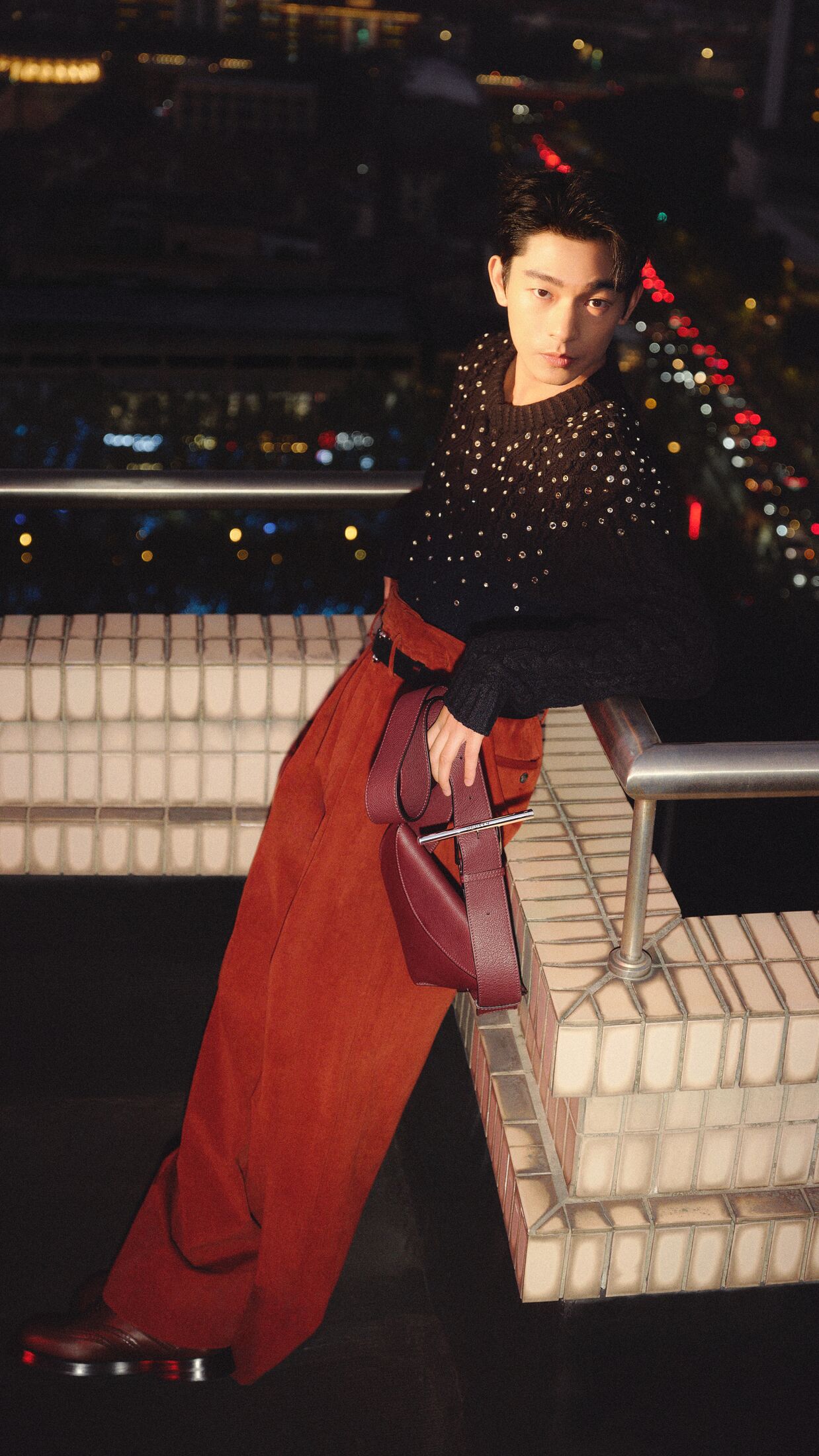 Man in red oversized trousers holding a burgundy sling bag