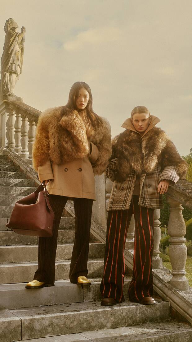 Two women in shearling winter coats and trousers