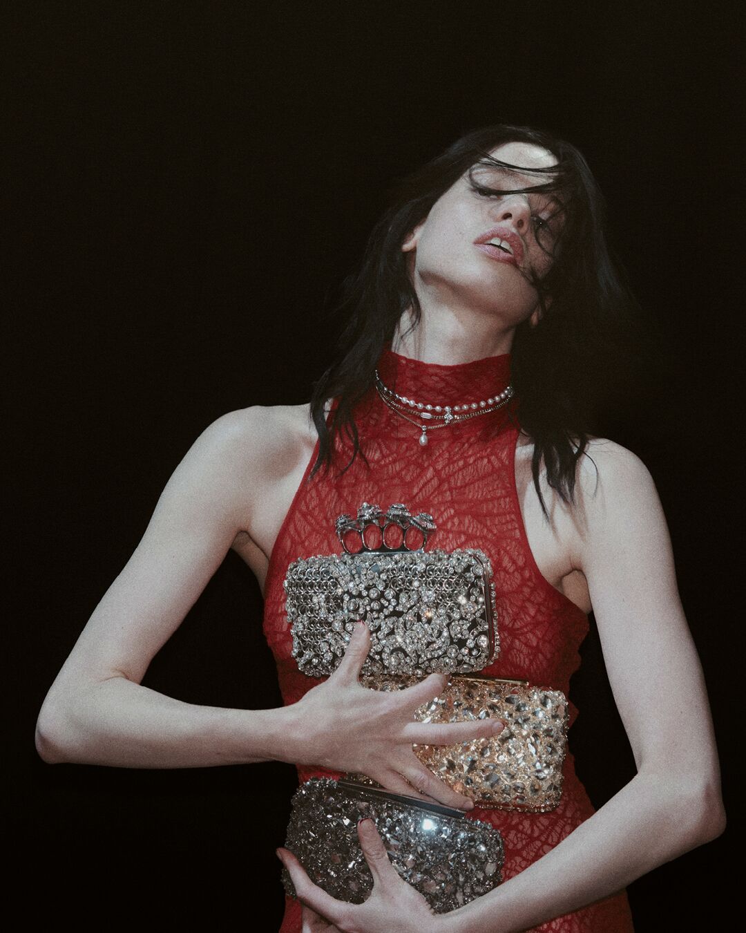 A person in a red dress holding McQueen clutches