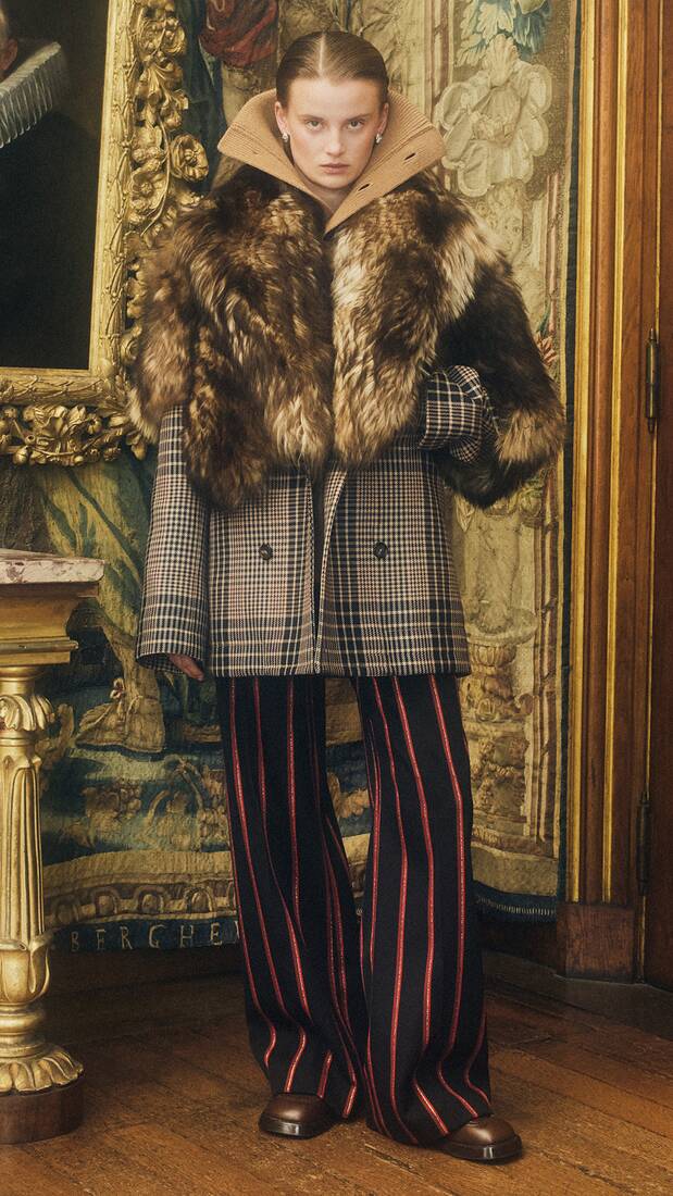 Women in shearling coat and pinstripe tailored trousers