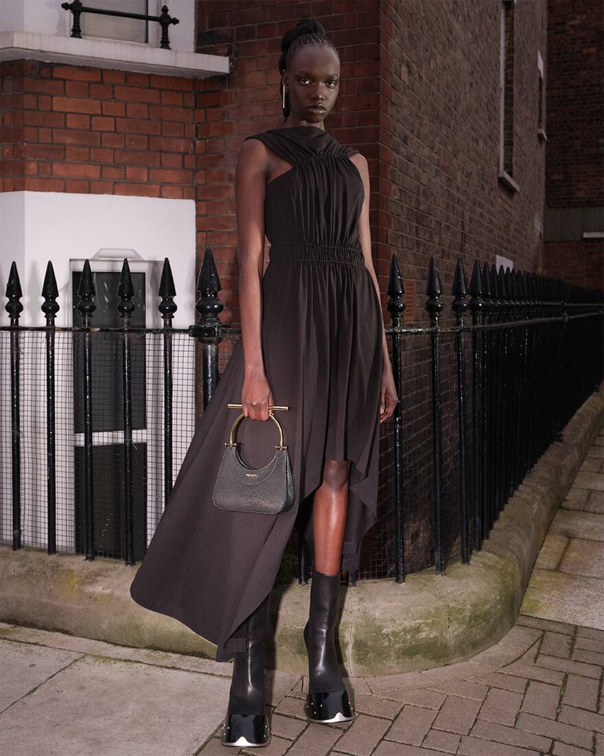 model wearing midi dress and boots while holding a bag
