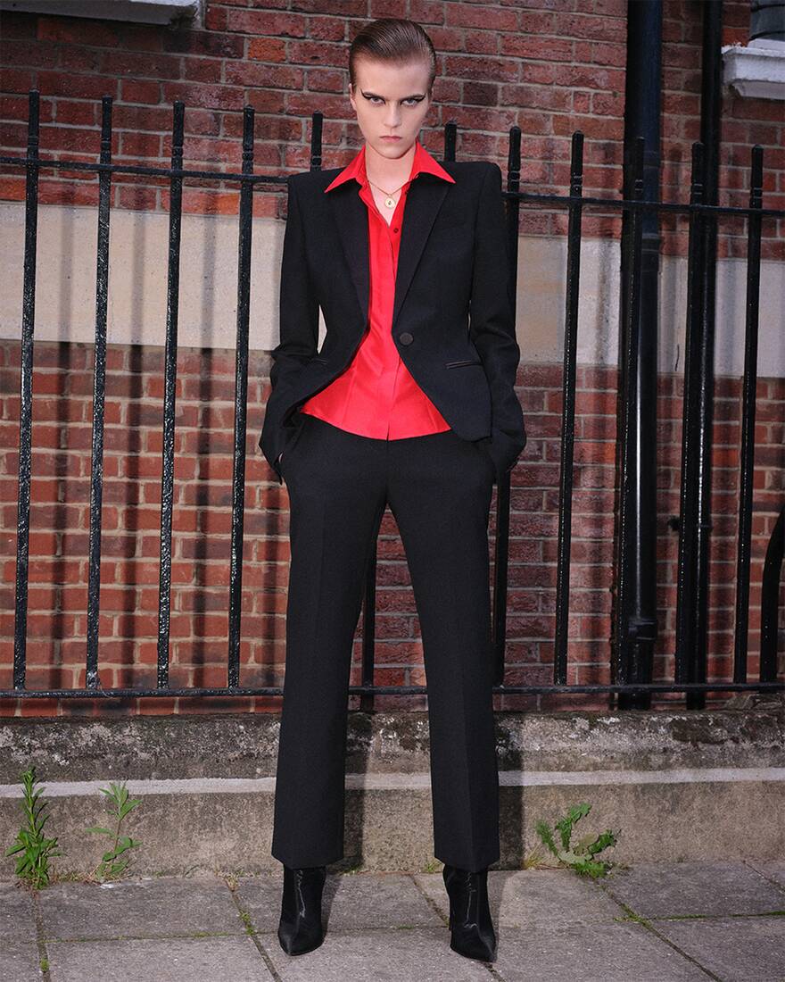 model in black tailored suit with red shirt