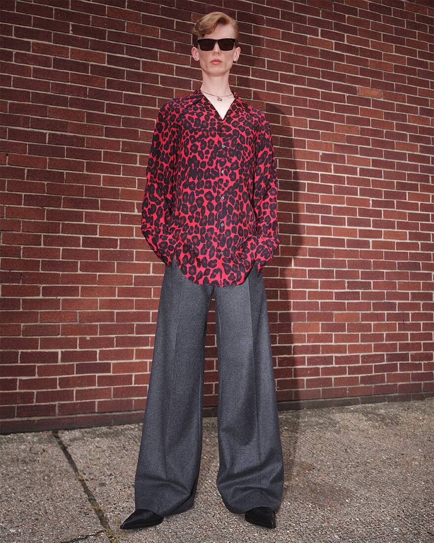 model wearing a shirt and trousers in front of a brick wall