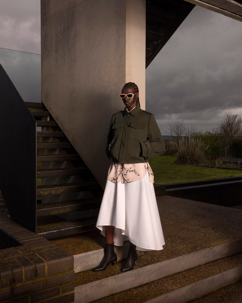 Model wearing kaki jacket over a blossom print skirt