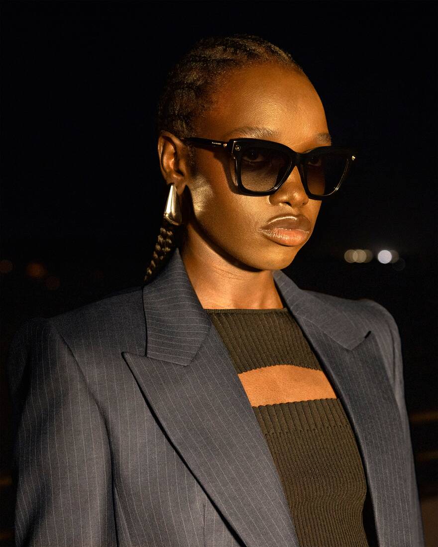 Model with sunglasses wearing pinstripe jacket with knit cut-out top underneath