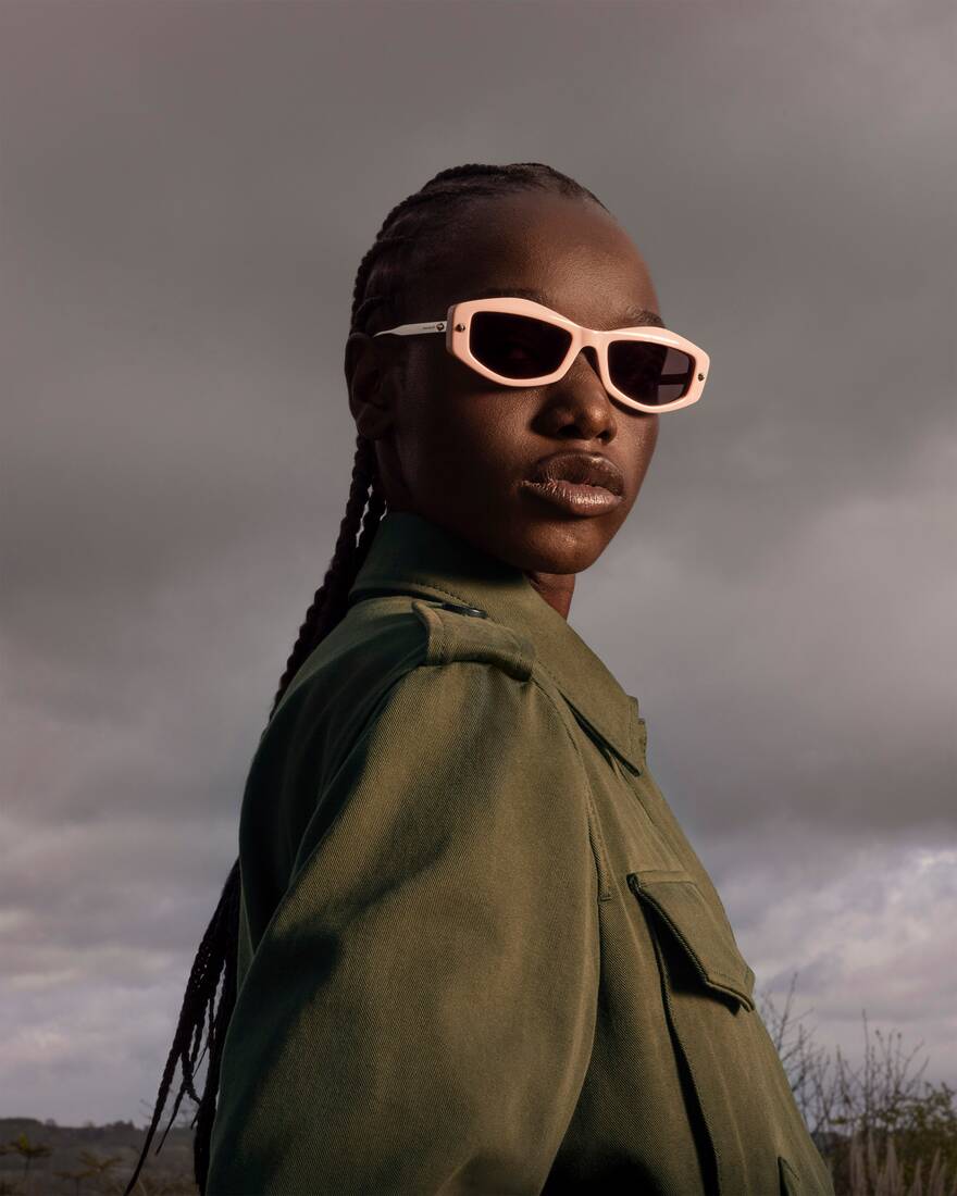 model wearing pink sunglasses against a cloudy sky